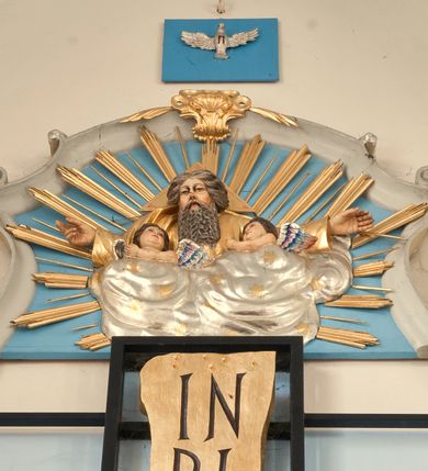 Zdjęcie nr 3: Ołtarz przyścienny, niearchitektoniczny, ze zwieńczeniem. Mensa kamienna w formie stołu wspartego na masywnych filarach. Na niej ustawione późnobarokowe tabernakulum z tronem wystawienia oraz figury świętych: św. Łukasza Ewangelisty oraz św. Benedykta z Nursji. Nastawa w formie ażurowej, metalowej konstrukcji w kształcie masywnego krzyża wspartego na trójdzielnej podstawie z prostokątów zakończonych trójkątnie. W polu ołtarza rzeźbiony krucyfiks umieszczony w prostokątnej, metalowej ramie na jasnobłękitnym tle. U szczytu pionowej belki krzyża titulus z apisem: IN/RI, na zakończeniach poziomej belki prostokątne tabliczki z greckimi literami: A i Ω. Po prawej stronie krucyfiksu umieszczony obraz z wizerunkiem Matki Boskiej Częstochowskiej w prostokątnej, bogato zdobionej akantem razie i złotej sukience. Zwieńczenie nastawy w formie barokowego szczytu o linii wklęsło-wypukłej mieszczącego w polu płaskorzeźbione przedstawienie Boga Ojca ukazującego się w obłokach w otoczeniu aniołów umieszczone na tle glorii promienistej. Szczyt ujęty jest spływami wolutowymi, na których ukazano siedzące putta. Ponad ołtarzem, na prostokątnym, błękitnym polu srebrzona gołębica Ducha Świętego.

