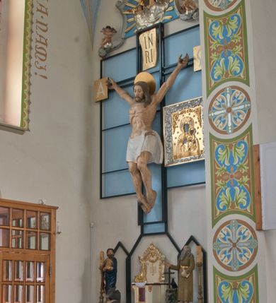 Zdjęcie nr 2: Ołtarz przyścienny, niearchitektoniczny, ze zwieńczeniem. Mensa kamienna w formie stołu wspartego na masywnych filarach. Na niej ustawione późnobarokowe tabernakulum z tronem wystawienia oraz figury świętych: św. Łukasza Ewangelisty oraz św. Benedykta z Nursji. Nastawa w formie ażurowej, metalowej konstrukcji w kształcie masywnego krzyża wspartego na trójdzielnej podstawie z prostokątów zakończonych trójkątnie. W polu ołtarza rzeźbiony krucyfiks umieszczony w prostokątnej, metalowej ramie na jasnobłękitnym tle. U szczytu pionowej belki krzyża titulus z apisem: IN/RI, na zakończeniach poziomej belki prostokątne tabliczki z greckimi literami: A i Ω. Po prawej stronie krucyfiksu umieszczony obraz z wizerunkiem Matki Boskiej Częstochowskiej w prostokątnej, bogato zdobionej akantem razie i złotej sukience. Zwieńczenie nastawy w formie barokowego szczytu o linii wklęsło-wypukłej mieszczącego w polu płaskorzeźbione przedstawienie Boga Ojca ukazującego się w obłokach w otoczeniu aniołów umieszczone na tle glorii promienistej. Szczyt ujęty jest spływami wolutowymi, na których ukazano siedzące putta. Ponad ołtarzem, na prostokątnym, błękitnym polu srebrzona gołębica Ducha Świętego.

