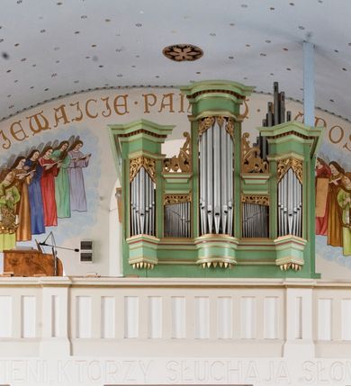 Zdjęcie nr 3: Prospekt organowy jednokondygnacyjny, pięcioosiowy o formach architektonicznych umieszczony na wysokim cokole.
Osie nieparzyste (pierwsza, trzecia i piąta) z większymi piszczałkami wypukłe, a pierwsza i piąta, na rzucie trójkąta niższe od środkowej. Wszystkie zwieńczone pełnym belkowaniem z wydatnym, profilowanym gzymsem dekorowanym kostkowaniem. W górnej części złocony, ażurowy lambrekin utworzony z ornamentu małżowinowo-chrząstkowego. Osie parzyste są niższe z płaskimi, prostokątnymi niszami mieszczącymi mniejsze piszczałki. Wieńczą je profilowano-fazowane konsole oraz ażurowe struktury z ornamentu małżowinowo-chrząstkowego. Prospekt polichromowany w odcieniach seledynowej zieleni z czerwonymi detalami, zaś ornamentyka i załamania profili architektonicznych złocone.