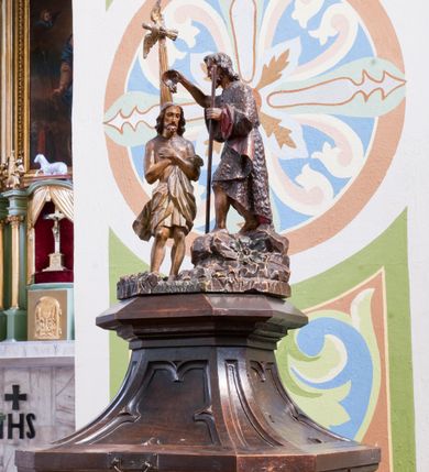 Zdjęcie nr 3: Chrzcielnica ustawiona na prostopadłościennej podstawie.  Profilowany cokół o przekroju prostokąta o ściętych narożach, trzon o takim samym przekroju ujęty u góry i u dołu profilowanymi wałkami. Czara spłaszczona o przekroju czworoboku o ściętych narożach; z wylewem. Pola z płycinową dekoracją peudomaswerkową. Pokrywa drewniana o dekoracji analogicznej jak czara, zwieńczona pełnoplastyczną, rzeźbioną sceną Chrztu Chrystusa.
