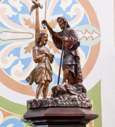 Zdjęcie nr 4: Chrzcielnica ustawiona na prostopadłościennej podstawie.  Profilowany cokół o przekroju prostokąta o ściętych narożach, trzon o takim samym przekroju ujęty u góry i u dołu profilowanymi wałkami. Czara spłaszczona o przekroju czworoboku o ściętych narożach; z wylewem. Pola z płycinową dekoracją peudomaswerkową. Pokrywa drewniana o dekoracji analogicznej jak czara, zwieńczona pełnoplastyczną, rzeźbioną sceną Chrztu Chrystusa.
