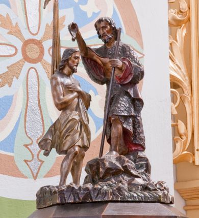 Zdjęcie nr 5: Chrzcielnica ustawiona na prostopadłościennej podstawie.  Profilowany cokół o przekroju prostokąta o ściętych narożach, trzon o takim samym przekroju ujęty u góry i u dołu profilowanymi wałkami. Czara spłaszczona o przekroju czworoboku o ściętych narożach; z wylewem. Pola z płycinową dekoracją peudomaswerkową. Pokrywa drewniana o dekoracji analogicznej jak czara, zwieńczona pełnoplastyczną, rzeźbioną sceną Chrztu Chrystusa.
