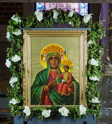 Zdjęcie nr 2: Feretron dwustronny, z prostopadłościenną podstawą z otworami na drążki. Na podstawie obrazy z przedstawieniem Matki Boskiej z Dzieciątkiem w typie Częstochowskiej oraz Matki Boskiej Niepokalanie Poczętej ujęte drewnianą, złoconą ramą. 
Matka Boska z Dzieciątkiem w typie Częstochowskiej Maria została ukazana w półpostaci, z Dzieciątkiem na lewym ramieniu, wskazując na nie drugą ręką. Patrzy na widza, ma duże, ciemne oczy, wąski nos i niewielkie usta; na prawym policzku dwa, równoległe nacięcia. Jest ubrana w czerwoną suknię w z wąskimi rękawami, obwiedzioną złotem przy szyi i przy mankietach, na którą ma zarzucony zielony maforion dekorowany złotym ornamentem roślinnym i lamowany taśmą ze szlachetnymi kamieniami. Dzieciątko prawą rękę unosi w geście błogosławieństwa, w lewej trzyma zamkniętą księgę. Ma owalną twarz, ciemne oczy, niewielki nos i usta. Jest ubrane w długą, czerwoną, dekorowaną drobnym ornamentem sukienkę z krzyżem łacińskim na piersi. Obie postacie mają na głowach zamknięte korony podtrzymywane przez anioły, a wokół złocone nimby. Tło jednolite, jasnozielone. 
Na drugim obrazie przedstawiono Matkę Boską w całej postaci, stojącą na ziemskim globie, lewą stopą depczącą węża, z półksiężycem przed stopami. Obie ręce ma rozłożone do boków, biją z nich w dół świetliste promienie, głowę skłania w prawo.  Ma owalną, delikatną twarz, spogląda przed siebie, ma szeroko otwarte oczy, wąski nos i niewielkie, czerwone usta oraz przykryte białym welonem długie włosy opadające na plecy. Na głowie korona, wokół niej wieniec z 12 gwiazd. Matka Boska jest ubrana w długą, białą suknię przewiązaną w talii paskiem oraz niebieski płaszcz lamowany złotem, zarzucony na plecy i spięty na dekolcie; stopy bose. Tło jasnoniebieskie, przechodzące dołem w skłębione obłoki. 
