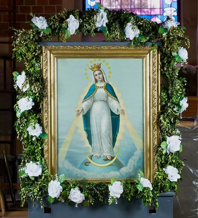 Zdjęcie nr 3: Feretron dwustronny, z prostopadłościenną podstawą z otworami na drążki. Na podstawie obrazy z przedstawieniem Matki Boskiej z Dzieciątkiem w typie Częstochowskiej oraz Matki Boskiej Niepokalanie Poczętej ujęte drewnianą, złoconą ramą. 
Matka Boska z Dzieciątkiem w typie Częstochowskiej Maria została ukazana w półpostaci, z Dzieciątkiem na lewym ramieniu, wskazując na nie drugą ręką. Patrzy na widza, ma duże, ciemne oczy, wąski nos i niewielkie usta; na prawym policzku dwa, równoległe nacięcia. Jest ubrana w czerwoną suknię w z wąskimi rękawami, obwiedzioną złotem przy szyi i przy mankietach, na którą ma zarzucony zielony maforion dekorowany złotym ornamentem roślinnym i lamowany taśmą ze szlachetnymi kamieniami. Dzieciątko prawą rękę unosi w geście błogosławieństwa, w lewej trzyma zamkniętą księgę. Ma owalną twarz, ciemne oczy, niewielki nos i usta. Jest ubrane w długą, czerwoną, dekorowaną drobnym ornamentem sukienkę z krzyżem łacińskim na piersi. Obie postacie mają na głowach zamknięte korony podtrzymywane przez anioły, a wokół złocone nimby. Tło jednolite, jasnozielone. 
Na drugim obrazie przedstawiono Matkę Boską w całej postaci, stojącą na ziemskim globie, lewą stopą depczącą węża, z półksiężycem przed stopami. Obie ręce ma rozłożone do boków, biją z nich w dół świetliste promienie, głowę skłania w prawo.  Ma owalną, delikatną twarz, spogląda przed siebie, ma szeroko otwarte oczy, wąski nos i niewielkie, czerwone usta oraz przykryte białym welonem długie włosy opadające na plecy. Na głowie korona, wokół niej wieniec z 12 gwiazd. Matka Boska jest ubrana w długą, białą suknię przewiązaną w talii paskiem oraz niebieski płaszcz lamowany złotem, zarzucony na plecy i spięty na dekolcie; stopy bose. Tło jasnoniebieskie, przechodzące dołem w skłębione obłoki. 
