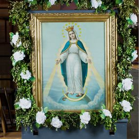 Zdjęcie nr 1: Feretron dwustronny, z prostopadłościenną podstawą z otworami na drążki. Na podstawie obrazy z przedstawieniem Matki Boskiej z Dzieciątkiem w typie Częstochowskiej oraz Matki Boskiej Niepokalanie Poczętej ujęte drewnianą, złoconą ramą. 
Matka Boska z Dzieciątkiem w typie Częstochowskiej Maria została ukazana w półpostaci, z Dzieciątkiem na lewym ramieniu, wskazując na nie drugą ręką. Patrzy na widza, ma duże, ciemne oczy, wąski nos i niewielkie usta; na prawym policzku dwa, równoległe nacięcia. Jest ubrana w czerwoną suknię w z wąskimi rękawami, obwiedzioną złotem przy szyi i przy mankietach, na którą ma zarzucony zielony maforion dekorowany złotym ornamentem roślinnym i lamowany taśmą ze szlachetnymi kamieniami. Dzieciątko prawą rękę unosi w geście błogosławieństwa, w lewej trzyma zamkniętą księgę. Ma owalną twarz, ciemne oczy, niewielki nos i usta. Jest ubrane w długą, czerwoną, dekorowaną drobnym ornamentem sukienkę z krzyżem łacińskim na piersi. Obie postacie mają na głowach zamknięte korony podtrzymywane przez anioły, a wokół złocone nimby. Tło jednolite, jasnozielone. 
Na drugim obrazie przedstawiono Matkę Boską w całej postaci, stojącą na ziemskim globie, lewą stopą depczącą węża, z półksiężycem przed stopami. Obie ręce ma rozłożone do boków, biją z nich w dół świetliste promienie, głowę skłania w prawo.  Ma owalną, delikatną twarz, spogląda przed siebie, ma szeroko otwarte oczy, wąski nos i niewielkie, czerwone usta oraz przykryte białym welonem długie włosy opadające na plecy. Na głowie korona, wokół niej wieniec z 12 gwiazd. Matka Boska jest ubrana w długą, białą suknię przewiązaną w talii paskiem oraz niebieski płaszcz lamowany złotem, zarzucony na plecy i spięty na dekolcie; stopy bose. Tło jasnoniebieskie, przechodzące dołem w skłębione obłoki. 
