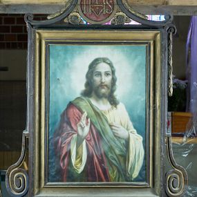 Zdjęcie nr 1: Feretron dwustronny, z prostopadłościenną podstawą z otworami na drążki. Na podstawie obrazy z przedstawieniem Chrystusa Błogosławiącego oraz Matki Boskiej z Dzieciątkiem otoczone drewnianą, profilowaną ramą zdobioną po bokach spłaszczonymi wolutami i zwieńczoną medalionem z monogramami „IHS” po jednej i „MARYA” po drugiej stronie, nad którym znajduje się zamknięta korona. Medalion ujmują c-kształtne elementy, a przestrzeń pod nimi wypełniają rozwinięte kwiaty.   
Na awersie Chrystus w półpostaci, który lewą rękę przyciska do piersi, a prawą unosi w geście błogosławieństwa. Na owalną twarz, duże ciemne oczy, wąski nos, niewielkie usta, wąsy oraz dzielącą się w dwa pukle brodę. Długie falowane włosy opadają mu na barki. Jest ubrany w żółtą suknię, przez prawy bark ma przerzucony czerwony płaszcz z zielonym podbiciem, wywinięty, łamiący się w obszerne fałdy. Wokół głowy postaci świetlisty nimb; tło stanowią niebieskie, skłębione obłoki. 
Na rewersie Matka Boska z Dzieciątkiem na prawym ramieniu, w półpostaci, frontalnie, z głową delikatnie przechyloną w prawo, lewą ręką przytrzymując Jezusa. Ma owalną twarz o delikatnych rysach, półprzymknięte oczy, wąski nos i szerokie usta, na głowie dekorowany pasem haftu, biały welon. Ubrana jest w czerwoną suknię z wąskimi rękawami i niebieski, podbity złotem płaszcz wywijający się przy prawej ręce. Dzieciątko siedzi, zwrócone w trzech czwartych w lewo, prawą ręką błogosławi, lewą dotyka dłoni Marii. Ma owalną, pulchną twarz o niebieskich oczach, małym nosie i ustach oraz jasne, falowane włosy. Jest ubrane w sukienkę białą górą, beżową dołem i przewiązaną fioletową szarfą w pasie; stopy bose. Postacie zostały ukazane na tle kamiennej balustrady, ponad którą widać rozłożyste drzewo i fragment ogrodu z kwitnący krzakiem róż po prawej stronie.