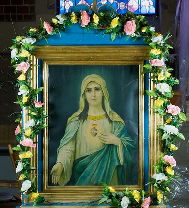 Zdjęcie nr 2: Feretron dwustronny, z prostopadłościenną podstawą z otworami na drążki. Na podstawie obrazy z przedstawieniem Najświętszego Serca Marii i Najświętszego Serca Jezusa otoczone drewnianą, profilowaną ramą zwieńczoną krzyżem łacińskim ujętym wolutami.
Na awersie Matka Boska została ukazana w półpostaci, frontalnie, patrząc przed siebie. Ma jasną karnację, rysy twarzy delikatne, oczy ciemne; ciemne, falowane włosy opadają jej na ramiona. Jest ubrana w białą lamowaną pod szyją złotem suknię, jasny, złocony na brzegach i opadający na barki welon, a na ramiona ma zarzucony błękitny, podbity jasnym materiałem płaszcz przechodzący na skos do prawego biodra. Prawą rękę wyciąga przed siebie, lewą wskazuje na widoczne na piersi gorejące serce oplecione różanym wieńcem. Tło przedstawienia ciemne, rozjaśnia się delikatnie wokół głowy Marii.  
Na rewersie ukazany w ten sam sposób Chrystus, który prawą rękę unosi w geście błogosławieństwa, a lewą wskazuje na oplecione koroną cierniową, płonące serce zwieńczone krzyżem. Jest ubrany w białą tunikę z długimi rękawami i  przerzucony przez lewe ramię czerwony płaszcz podbity złotem. 
