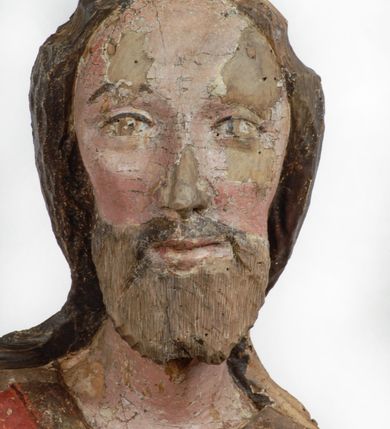 Zdjęcie nr 2: Rzeźba pełnoplastyczna, z tyłu opracowana, drążona wewnątrz, ustawiona na wielobocznej podstawie. Chrystus ukazany frontalnie, w pozycji stojącej, w lekkim kontrapoście, z prawą stopą wysuniętą do przodu, korpus przechylony w lewą stronę, prawy bark podniesiony wyżej od lewego. Prawa ręka wzniesiona ku górze w geście błogosławieństwa, lewa mocno przylega do ciała w okolicy żeber, ugięta w łokciu, w której trzyma drzewce proporca. Twarz pociągła o karnacji cielistej, z zaróżowionymi policzkami, wysokie czoło, szeroko rozstawione, podłużne oczy ze źrenicami i zarysowaną powieką, zaznaczone brwi cienką kreską, długi, prosty nos, wąskie usta. Okala ją zarost oraz długie, gładkie, delikatnie sfalowane włosy, z przedziałkiem, zasłaniające uszy i opadające na kark oraz plecy. W prawym boku i na stopach wyraźne rany. Odziany jest w szatę upiętą pod szyją, w czerwonym kolorze z ciemno- granatową podszewką i złotą lamówką, odsłaniającą tors i wklęsły brzuch, z prawą połą przerzuconą z przodu pod prawą ręką i zawiniętą wokół lewego przedramienia. Fałdy płaszcza są załamane ostro, diagonalnie i nieckowato. Na boku, stopie i lewej ręce zaznaczone rany.