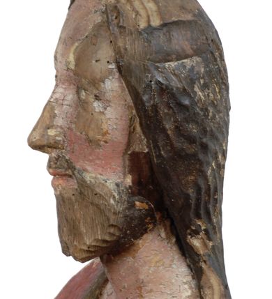 Zdjęcie nr 6: Rzeźba pełnoplastyczna, z tyłu opracowana, drążona wewnątrz, ustawiona na wielobocznej podstawie. Chrystus ukazany frontalnie, w pozycji stojącej, w lekkim kontrapoście, z prawą stopą wysuniętą do przodu, korpus przechylony w lewą stronę, prawy bark podniesiony wyżej od lewego. Prawa ręka wzniesiona ku górze w geście błogosławieństwa, lewa mocno przylega do ciała w okolicy żeber, ugięta w łokciu, w której trzyma drzewce proporca. Twarz pociągła o karnacji cielistej, z zaróżowionymi policzkami, wysokie czoło, szeroko rozstawione, podłużne oczy ze źrenicami i zarysowaną powieką, zaznaczone brwi cienką kreską, długi, prosty nos, wąskie usta. Okala ją zarost oraz długie, gładkie, delikatnie sfalowane włosy, z przedziałkiem, zasłaniające uszy i opadające na kark oraz plecy. W prawym boku i na stopach wyraźne rany. Odziany jest w szatę upiętą pod szyją, w czerwonym kolorze z ciemno- granatową podszewką i złotą lamówką, odsłaniającą tors i wklęsły brzuch, z prawą połą przerzuconą z przodu pod prawą ręką i zawiniętą wokół lewego przedramienia. Fałdy płaszcza są załamane ostro, diagonalnie i nieckowato. Na boku, stopie i lewej ręce zaznaczone rany.