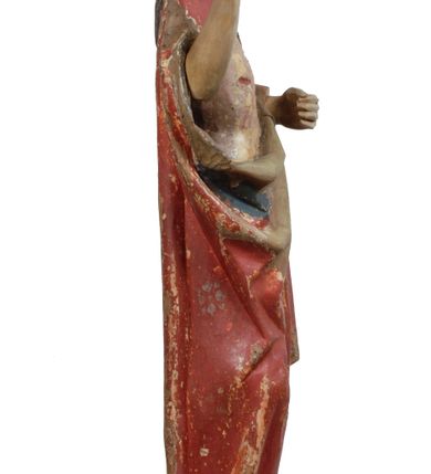 Zdjęcie nr 13: Rzeźba pełnoplastyczna, z tyłu opracowana, drążona wewnątrz, ustawiona na wielobocznej podstawie. Chrystus ukazany frontalnie, w pozycji stojącej, w lekkim kontrapoście, z prawą stopą wysuniętą do przodu, korpus przechylony w lewą stronę, prawy bark podniesiony wyżej od lewego. Prawa ręka wzniesiona ku górze w geście błogosławieństwa, lewa mocno przylega do ciała w okolicy żeber, ugięta w łokciu, w której trzyma drzewce proporca. Twarz pociągła o karnacji cielistej, z zaróżowionymi policzkami, wysokie czoło, szeroko rozstawione, podłużne oczy ze źrenicami i zarysowaną powieką, zaznaczone brwi cienką kreską, długi, prosty nos, wąskie usta. Okala ją zarost oraz długie, gładkie, delikatnie sfalowane włosy, z przedziałkiem, zasłaniające uszy i opadające na kark oraz plecy. W prawym boku i na stopach wyraźne rany. Odziany jest w szatę upiętą pod szyją, w czerwonym kolorze z ciemno- granatową podszewką i złotą lamówką, odsłaniającą tors i wklęsły brzuch, z prawą połą przerzuconą z przodu pod prawą ręką i zawiniętą wokół lewego przedramienia. Fałdy płaszcza są załamane ostro, diagonalnie i nieckowato. Na boku, stopie i lewej ręce zaznaczone rany.