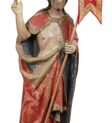 Zdjęcie nr 15: Rzeźba pełnoplastyczna, z tyłu opracowana, drążona wewnątrz, ustawiona na wielobocznej podstawie. Chrystus ukazany frontalnie, w pozycji stojącej, w lekkim kontrapoście, z prawą stopą wysuniętą do przodu, korpus przechylony w lewą stronę, prawy bark podniesiony wyżej od lewego. Prawa ręka wzniesiona ku górze w geście błogosławieństwa, lewa mocno przylega do ciała w okolicy żeber, ugięta w łokciu, w której trzyma drzewce proporca. Twarz pociągła o karnacji cielistej, z zaróżowionymi policzkami, wysokie czoło, szeroko rozstawione, podłużne oczy ze źrenicami i zarysowaną powieką, zaznaczone brwi cienką kreską, długi, prosty nos, wąskie usta. Okala ją zarost oraz długie, gładkie, delikatnie sfalowane włosy, z przedziałkiem, zasłaniające uszy i opadające na kark oraz plecy. W prawym boku i na stopach wyraźne rany. Odziany jest w szatę upiętą pod szyją, w czerwonym kolorze z ciemno- granatową podszewką i złotą lamówką, odsłaniającą tors i wklęsły brzuch, z prawą połą przerzuconą z przodu pod prawą ręką i zawiniętą wokół lewego przedramienia. Fałdy płaszcza są załamane ostro, diagonalnie i nieckowato. Na boku, stopie i lewej ręce zaznaczone rany.