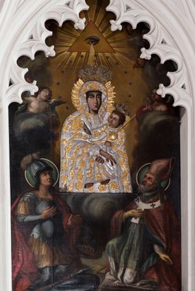 Zdjęcie nr 1: Obraz o kształcie stojącego prostokąta zamkniętego łukiem ostrym. Pośrodku, wśród obłoków przedstawienie Matki Boskiej z Dzieciątkiem na lewym ramieniu, w półpostaci, zwrócona lekko w lewo, z dłońmi skrzyżowanymi w okolicach kolan Chrystusa. Po bokach adorujący dwaj aniołowie Poniżej w narożach kompozycji klęczą po stronie lewej św. Jerzy, po prawej św. Wojciech. Ponad Marią Oko Opatrzności. Matka Boska ubrana jest w czerwoną suknię ze złotą lamówką, na która narzucony ma błękitny płaszcz z kwiatami o żółtych środkach. Głowę wieńczy dekoracyjna korona, podobnie jak Jezusa. Chrystus ukazany jest en trois quarts, w swobodnej pozycji, lewą ręką podtrzymuje  księgę włożoną pod pachę, prawą unosi w geście błogosławieństwa. Ubrany jest w długą sukienkę z długimi rękawami, przewiązaną paskiem, odsłaniającą stopy.  Św. Jerzy, w zbroi i czerwonym płaszczu narzuconym na ramiona, prawą rękę przyłożył do klatki piersiowej, lewą unosi w okolicy tułowia. Na głowie ma hełm z pióropuszem, spod którego widać długie, kręcone włosy opadające na kark. Przy lewym jego boku widoczna jest głowa zabitego smoka. Św. Wojciech, w stroju pontyfikalnym, z paliuszem na ramionach, prawą rękę położył na klatce piersiowej, lewą podtrzymuje połę kapy liturgicznej. Wokół głów świętych koliste nimby. 