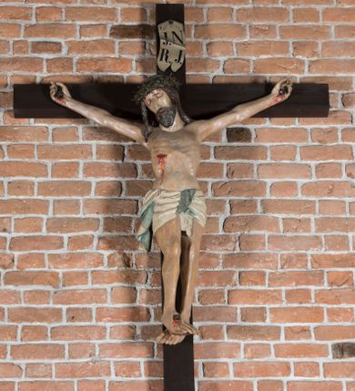 Zdjęcie nr 1: Rzeźba pełnoplastyczna, polichromowana. Chrystus w niezbyt głębokim zwisie o sztywnych, mocno napiętych, rozpostartych ramionach i delikatnie zwiniętych palcach. Nogi wyprostowane, skierowane do wewnątrz, dosyć duże stopy nałożone prawa na lewą i przybite jednym gwoździem. Na biodrach krótkie perizonium, z przewagą fałd pionowych, opada na prawym boku kaskadą, z kolei drugi koniec wywinięty na perizonium i spływa na lewe udo. Głowa lekko pochylona w kierunku prawego ramienia, oczy zamknięte, brwi opadające w kierunku skroni, nos prosty, długi, twarz pociągła o wyraźnych kościach policzkowych, usta wąskie, lekko uchylone, okolone przez schematycznie opracowaną w symetryczne rowki brodę. Na głowie korona cierniowa w formie dwóch wałków z licznymi kolcami, spod której opada na prawe ramię cienkie pasmo schematycznie rytych włosów. Z miejsc po przebiciu gwoździami, z rany zadanej w boku oraz spod korony cierniowej spływa krew. Karnacja Chrystusa dosyć jasna, z odcieniem szarości. Krzyż, zarost, włosy, korona cierniowa w kolorze ciemnobrązowym, perizonium białe. W górnej części pionowej belki krzyża zawieszona w pionie tabliczka, dosyć długa, o zwiniętych do wewnątrz końcach, z trójkątnymi wycięciami na środku brzegów, z napisem „I.N.R.I”.