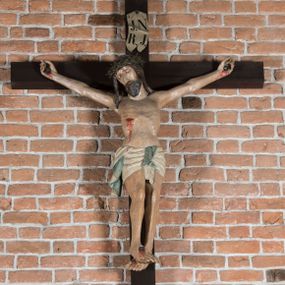 Zdjęcie nr 1: Rzeźba pełnoplastyczna, polichromowana. Chrystus w niezbyt głębokim zwisie o sztywnych, mocno napiętych, rozpostartych ramionach i delikatnie zwiniętych palcach. Nogi wyprostowane, skierowane do wewnątrz, dosyć duże stopy nałożone prawa na lewą i przybite jednym gwoździem. Na biodrach krótkie perizonium, z przewagą fałd pionowych, opada na prawym boku kaskadą, z kolei drugi koniec wywinięty na perizonium i spływa na lewe udo. Głowa lekko pochylona w kierunku prawego ramienia, oczy zamknięte, brwi opadające w kierunku skroni, nos prosty, długi, twarz pociągła o wyraźnych kościach policzkowych, usta wąskie, lekko uchylone, okolone przez schematycznie opracowaną w symetryczne rowki brodę. Na głowie korona cierniowa w formie dwóch wałków z licznymi kolcami, spod której opada na prawe ramię cienkie pasmo schematycznie rytych włosów. Z miejsc po przebiciu gwoździami, z rany zadanej w boku oraz spod korony cierniowej spływa krew. Karnacja Chrystusa dosyć jasna, z odcieniem szarości. Krzyż, zarost, włosy, korona cierniowa w kolorze ciemnobrązowym, perizonium białe. W górnej części pionowej belki krzyża zawieszona w pionie tabliczka, dosyć długa, o zwiniętych do wewnątrz końcach, z trójkątnymi wycięciami na środku brzegów, z napisem „I.N.R.I”.