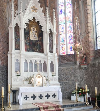 Zdjęcie nr 3: Neogotycki ołtarz główny w kolorze naturalnego wapienia, architektoniczny, wolnostojący, trójosiowy, z wydzieloną częścią cokołową, dwukondygnacyjny, ze zwieńczeniem. Mensa skrzyniowa, ujęta dwiema kolumienkami. Antependium ozdobione płycinami w kształcie czworoliści. Nastawa artykułowana w dolnej kondygnacji czworobocznymi półfilarami, w górnej kondygnacji kolumienkami o liściastych kapitelach, z opaskami w połowie wysokości, przechodzącymi w zwieńczeniu w pinakle. Dolna kondygnacja dwustrefowa. W strefie dolnej stylizowana wić roślinna i tarcze herbowe. W strefie górnej nisze zamknięte trójlistnie (na relikwiarze?), w osi środkowej pięć, w osiach skrajnych po jednej. W kondygnacji górnej nisze, środkowa szeroka, zamknięta ostrołukowo z maswerkowaniem w podłuczu, w osiach skrajnych wąskie, zamknięte trójlistnie. W niszy środkowej obraz Adoracja Matki Boskiej Śnieżnej przez śś. Wojciecha i Jerzego, po bokach obrazy: po prawej Św. Florian, z sygnaturą w dolnej części -  S. Bryniarski / pinxit 1886; po lewej postać kobiety w prawej ręce ze zwojem z napisem: EWAN/GELJA, z sygnaturą u dołu - S. Bryniarski / malował. W zwieńczeniu pomiędzy pinaklami trójkątne szczyty z żabkami na krawędziach, środkowy w polu z rozetą z Gołębicą Ducha Świętego na złotym tle, zakończony krzyżem. 