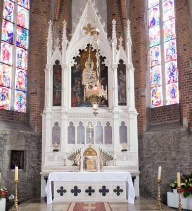 Zdjęcie nr 32: Neogotycki ołtarz główny w kolorze naturalnego wapienia, architektoniczny, wolnostojący, trójosiowy, z wydzieloną częścią cokołową, dwukondygnacyjny, ze zwieńczeniem. Mensa skrzyniowa, ujęta dwiema kolumienkami. Antependium ozdobione płycinami w kształcie czworoliści. Nastawa artykułowana w dolnej kondygnacji czworobocznymi półfilarami, w górnej kondygnacji kolumienkami o liściastych kapitelach, z opaskami w połowie wysokości, przechodzącymi w zwieńczeniu w pinakle. Dolna kondygnacja dwustrefowa. W strefie dolnej stylizowana wić roślinna i tarcze herbowe. W strefie górnej nisze zamknięte trójlistnie (na relikwiarze?), w osi środkowej pięć, w osiach skrajnych po jednej. W kondygnacji górnej nisze, środkowa szeroka, zamknięta ostrołukowo z maswerkowaniem w podłuczu, w osiach skrajnych wąskie, zamknięte trójlistnie. W niszy środkowej obraz Adoracja Matki Boskiej Śnieżnej przez śś. Wojciecha i Jerzego, po bokach obrazy: po prawej Św. Florian, z sygnaturą w dolnej części -  S. Bryniarski / pinxit 1886; po lewej postać kobiety w prawej ręce ze zwojem z napisem: EWAN/GELJA, z sygnaturą u dołu - S. Bryniarski / malował. W zwieńczeniu pomiędzy pinaklami trójkątne szczyty z żabkami na krawędziach, środkowy w polu z rozetą z Gołębicą Ducha Świętego na złotym tle, zakończony krzyżem. 