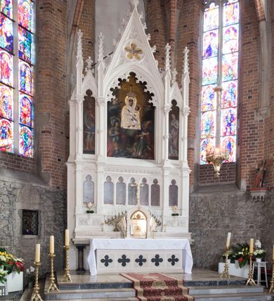 Zdjęcie nr 31: Neogotycki ołtarz główny w kolorze naturalnego wapienia, architektoniczny, wolnostojący, trójosiowy, z wydzieloną częścią cokołową, dwukondygnacyjny, ze zwieńczeniem. Mensa skrzyniowa, ujęta dwiema kolumienkami. Antependium ozdobione płycinami w kształcie czworoliści. Nastawa artykułowana w dolnej kondygnacji czworobocznymi półfilarami, w górnej kondygnacji kolumienkami o liściastych kapitelach, z opaskami w połowie wysokości, przechodzącymi w zwieńczeniu w pinakle. Dolna kondygnacja dwustrefowa. W strefie dolnej stylizowana wić roślinna i tarcze herbowe. W strefie górnej nisze zamknięte trójlistnie (na relikwiarze?), w osi środkowej pięć, w osiach skrajnych po jednej. W kondygnacji górnej nisze, środkowa szeroka, zamknięta ostrołukowo z maswerkowaniem w podłuczu, w osiach skrajnych wąskie, zamknięte trójlistnie. W niszy środkowej obraz Adoracja Matki Boskiej Śnieżnej przez śś. Wojciecha i Jerzego, po bokach obrazy: po prawej Św. Florian, z sygnaturą w dolnej części -  S. Bryniarski / pinxit 1886; po lewej postać kobiety w prawej ręce ze zwojem z napisem: EWAN/GELJA, z sygnaturą u dołu - S. Bryniarski / malował. W zwieńczeniu pomiędzy pinaklami trójkątne szczyty z żabkami na krawędziach, środkowy w polu z rozetą z Gołębicą Ducha Świętego na złotym tle, zakończony krzyżem. 