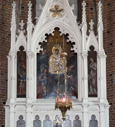 Zdjęcie nr 11: Neogotycki ołtarz główny w kolorze naturalnego wapienia, architektoniczny, wolnostojący, trójosiowy, z wydzieloną częścią cokołową, dwukondygnacyjny, ze zwieńczeniem. Mensa skrzyniowa, ujęta dwiema kolumienkami. Antependium ozdobione płycinami w kształcie czworoliści. Nastawa artykułowana w dolnej kondygnacji czworobocznymi półfilarami, w górnej kondygnacji kolumienkami o liściastych kapitelach, z opaskami w połowie wysokości, przechodzącymi w zwieńczeniu w pinakle. Dolna kondygnacja dwustrefowa. W strefie dolnej stylizowana wić roślinna i tarcze herbowe. W strefie górnej nisze zamknięte trójlistnie (na relikwiarze?), w osi środkowej pięć, w osiach skrajnych po jednej. W kondygnacji górnej nisze, środkowa szeroka, zamknięta ostrołukowo z maswerkowaniem w podłuczu, w osiach skrajnych wąskie, zamknięte trójlistnie. W niszy środkowej obraz Adoracja Matki Boskiej Śnieżnej przez śś. Wojciecha i Jerzego, po bokach obrazy: po prawej Św. Florian, z sygnaturą w dolnej części -  S. Bryniarski / pinxit 1886; po lewej postać kobiety w prawej ręce ze zwojem z napisem: EWAN/GELJA, z sygnaturą u dołu - S. Bryniarski / malował. W zwieńczeniu pomiędzy pinaklami trójkątne szczyty z żabkami na krawędziach, środkowy w polu z rozetą z Gołębicą Ducha Świętego na złotym tle, zakończony krzyżem. 