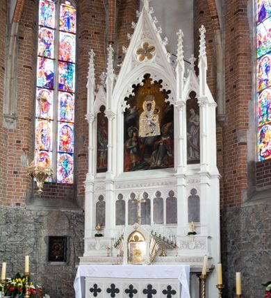 Zdjęcie nr 22: Neogotycki ołtarz główny w kolorze naturalnego wapienia, architektoniczny, wolnostojący, trójosiowy, z wydzieloną częścią cokołową, dwukondygnacyjny, ze zwieńczeniem. Mensa skrzyniowa, ujęta dwiema kolumienkami. Antependium ozdobione płycinami w kształcie czworoliści. Nastawa artykułowana w dolnej kondygnacji czworobocznymi półfilarami, w górnej kondygnacji kolumienkami o liściastych kapitelach, z opaskami w połowie wysokości, przechodzącymi w zwieńczeniu w pinakle. Dolna kondygnacja dwustrefowa. W strefie dolnej stylizowana wić roślinna i tarcze herbowe. W strefie górnej nisze zamknięte trójlistnie (na relikwiarze?), w osi środkowej pięć, w osiach skrajnych po jednej. W kondygnacji górnej nisze, środkowa szeroka, zamknięta ostrołukowo z maswerkowaniem w podłuczu, w osiach skrajnych wąskie, zamknięte trójlistnie. W niszy środkowej obraz Adoracja Matki Boskiej Śnieżnej przez śś. Wojciecha i Jerzego, po bokach obrazy: po prawej Św. Florian, z sygnaturą w dolnej części -  S. Bryniarski / pinxit 1886; po lewej postać kobiety w prawej ręce ze zwojem z napisem: EWAN/GELJA, z sygnaturą u dołu - S. Bryniarski / malował. W zwieńczeniu pomiędzy pinaklami trójkątne szczyty z żabkami na krawędziach, środkowy w polu z rozetą z Gołębicą Ducha Świętego na złotym tle, zakończony krzyżem. 