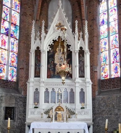 Zdjęcie nr 23: Neogotycki ołtarz główny w kolorze naturalnego wapienia, architektoniczny, wolnostojący, trójosiowy, z wydzieloną częścią cokołową, dwukondygnacyjny, ze zwieńczeniem. Mensa skrzyniowa, ujęta dwiema kolumienkami. Antependium ozdobione płycinami w kształcie czworoliści. Nastawa artykułowana w dolnej kondygnacji czworobocznymi półfilarami, w górnej kondygnacji kolumienkami o liściastych kapitelach, z opaskami w połowie wysokości, przechodzącymi w zwieńczeniu w pinakle. Dolna kondygnacja dwustrefowa. W strefie dolnej stylizowana wić roślinna i tarcze herbowe. W strefie górnej nisze zamknięte trójlistnie (na relikwiarze?), w osi środkowej pięć, w osiach skrajnych po jednej. W kondygnacji górnej nisze, środkowa szeroka, zamknięta ostrołukowo z maswerkowaniem w podłuczu, w osiach skrajnych wąskie, zamknięte trójlistnie. W niszy środkowej obraz Adoracja Matki Boskiej Śnieżnej przez śś. Wojciecha i Jerzego, po bokach obrazy: po prawej Św. Florian, z sygnaturą w dolnej części -  S. Bryniarski / pinxit 1886; po lewej postać kobiety w prawej ręce ze zwojem z napisem: EWAN/GELJA, z sygnaturą u dołu - S. Bryniarski / malował. W zwieńczeniu pomiędzy pinaklami trójkątne szczyty z żabkami na krawędziach, środkowy w polu z rozetą z Gołębicą Ducha Świętego na złotym tle, zakończony krzyżem. 