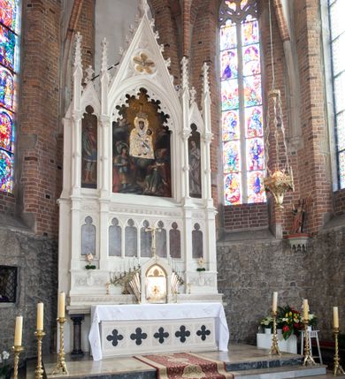 Zdjęcie nr 25: Neogotycki ołtarz główny w kolorze naturalnego wapienia, architektoniczny, wolnostojący, trójosiowy, z wydzieloną częścią cokołową, dwukondygnacyjny, ze zwieńczeniem. Mensa skrzyniowa, ujęta dwiema kolumienkami. Antependium ozdobione płycinami w kształcie czworoliści. Nastawa artykułowana w dolnej kondygnacji czworobocznymi półfilarami, w górnej kondygnacji kolumienkami o liściastych kapitelach, z opaskami w połowie wysokości, przechodzącymi w zwieńczeniu w pinakle. Dolna kondygnacja dwustrefowa. W strefie dolnej stylizowana wić roślinna i tarcze herbowe. W strefie górnej nisze zamknięte trójlistnie (na relikwiarze?), w osi środkowej pięć, w osiach skrajnych po jednej. W kondygnacji górnej nisze, środkowa szeroka, zamknięta ostrołukowo z maswerkowaniem w podłuczu, w osiach skrajnych wąskie, zamknięte trójlistnie. W niszy środkowej obraz Adoracja Matki Boskiej Śnieżnej przez śś. Wojciecha i Jerzego, po bokach obrazy: po prawej Św. Florian, z sygnaturą w dolnej części -  S. Bryniarski / pinxit 1886; po lewej postać kobiety w prawej ręce ze zwojem z napisem: EWAN/GELJA, z sygnaturą u dołu - S. Bryniarski / malował. W zwieńczeniu pomiędzy pinaklami trójkątne szczyty z żabkami na krawędziach, środkowy w polu z rozetą z Gołębicą Ducha Świętego na złotym tle, zakończony krzyżem. 