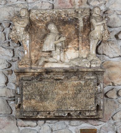 Zdjęcie nr 1: Epitafium złożone z dwóch płyt w kształcie leżącego prostokąta: u dołu płyta z inskrypcją, w obramieniu z ornamentem kartuszowo-zawijanym; ponad nią płaskorzeźbiona płyta z figuralnym przedstawieniem, flankowana dwiema groteskowymi hermami kobiet z biodrami okrytymi liśćmi akantu, stojące na grubych, lwich łapach, trzymające kiście winogron. W polu górnej płyty klęcząca postać zmarłego, ukazana z profilu, ze złożonymi w geście modlitwy rękoma, adorującego krucyfiks. W dłoniach trzyma różaniec. Twarz okala długa, spiczasta broda, wąsy oraz krótkie włosy odsłaniające prawe ucho. Przedstawiony jest w zbroi, krótkiej pelerynie przerzuconej na plecy. Ciało Chrystusa w lekkim zwisie, pochylone jest w kierunku prawego ramienia. Ponad sceną schematycznie opracowane obłoki o kształcie małżowin. Inskrypcja na dolnej płycie majuskułą po łacinie: D.O.M. / ANDREAE BRONOWSKY DE BRONOW EX DISTRICTV PLOCENSI / INSIGNI FAMILIA INPRIMIS QVE PARENTIBVS NOBILISS/IMIS PROCREATO PRVDENTIA ANIMI MAGNITVDINE / PIETATE ACCAE TERIS VIRTVTIBVS DOMIINE X TERISQVE / NATIONIBVS CLARISSIMO HAEREDES BENEFACTORI / SVO MAERENTES POSVERVNT OBIT A GENSANNVM / LVI DIE XXIX APRILIS ANNO MDCXII. Poniżej epitafium znajduje się tabliczka z informacją: „EPITAFIUM JĘDZRZEJA BRONOWSKIEGO PRZENIESIONO DO WNĘTRZA KOŚCIOŁA W 1996 R. STARANIEM PROBOSZCZA KS. CZESŁAWA PUTO I KONSERWATORA MGR DANUTY MAJEWSKIEJ ORAZ POŚWIĘCONO PONOWNIE Z UDZIAŁEM CZŁONKÓW STOWARZYSZENIA BRONOWSKICH H. KORAB.