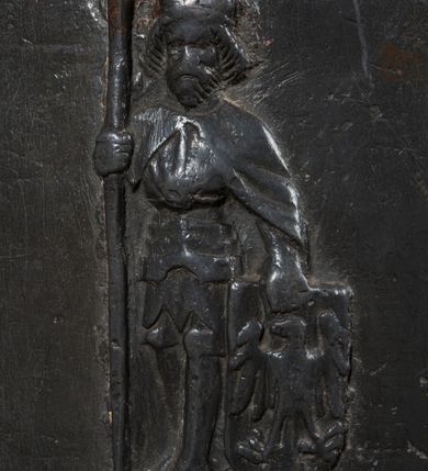 Zdjęcie nr 4: Chrzcielnica gotycka w kształcie kielicha. Posiada kolistą stopę, która przechodzi w stożkowato zwężającą się tuleję z wydatnym wałkiem w połowie wysokości. Czara dołem lekko zaokrąglona, rozchylająca się ku górze. Płaszcz dekorowany u dołu i poniżej górnej krawędzi wąskimi pasami z minuskułowymi napisami, przedzielone motywem lilii:  MARIA ROSA ROT HIS UNS, ANNO DOMINI 1462. Pomiędzy nimi rozmieszczone są na obwodzie cztery plakietki przedstawiające trójpostaciową Grupę Ukrzyżowania oraz frontalny wizerunek księcia zatorskiego Wacława w całej postaci. W prawej ręce trzyma włócznię, lewą dłoń opiera na tarczy z orłem. Twarz okala broda zakończona w szpic oraz długie i sfalowane włosy. Głowę wieńczy niewysoka książęca mitra. Ubrany jest w długi płaszcz narzucony na późnogotycka zbroję. Drewniana pokrywa chrzcielnicy została dodana wtórnie.