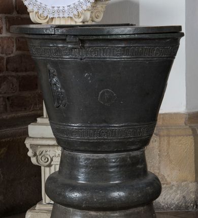 Zdjęcie nr 1: Chrzcielnica gotycka w kształcie kielicha. Posiada kolistą stopę, która przechodzi w stożkowato zwężającą się tuleję z wydatnym wałkiem w połowie wysokości. Czara dołem lekko zaokrąglona, rozchylająca się ku górze. Płaszcz dekorowany u dołu i poniżej górnej krawędzi wąskimi pasami z minuskułowymi napisami, przedzielone motywem lilii:  MARIA ROSA ROT HIS UNS, ANNO DOMINI 1462. Pomiędzy nimi rozmieszczone są na obwodzie cztery plakietki przedstawiające trójpostaciową Grupę Ukrzyżowania oraz frontalny wizerunek księcia zatorskiego Wacława w całej postaci. W prawej ręce trzyma włócznię, lewą dłoń opiera na tarczy z orłem. Twarz okala broda zakończona w szpic oraz długie i sfalowane włosy. Głowę wieńczy niewysoka książęca mitra. Ubrany jest w długi płaszcz narzucony na późnogotycka zbroję. Drewniana pokrywa chrzcielnicy została dodana wtórnie.