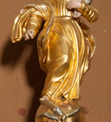 Zdjęcie nr 2: Stopa na planie koła, spłaszczona, na cokole. Trzon w formie dwulalkowej tralki, z pierścieniem w kształcie skręconego sznura pośrodku. Czara półkolista, gładka, u jej podstawy pierścień w kształcie skręconego sznura. Pokrywa drewniana, na planie koła, w formie cokołu z czterema wolutami dekorowanymi rocaille'em, tworzącymi podstawę dla figurki Matki Boskiej Niepokalanie Poczętej. Maria ukazana frontalnie, w kontrapoście, stoi na globie, posadowionym na obłokach z uskrzydlonymi główkami anielskimi. Lewą ręką podtrzymuje Dzieciątko, prawą wyciąga w przód, prawą stopą depcze węża. Twarz ma okrągłą, o schematycznie zaznaczonych rysach. Ubrana jest w suknię przylegającą do ciała, przepasaną w talii oraz płaszcz zawiązany na prawym ramieniu, na głowie ma welon. Pokrywa polichromowana w kolorze białym, ornamentyka i strój Marii złocony, detal srebrzony, elementy anatomiczne malowane naturalistycznie. 



