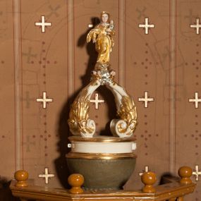 Zdjęcie nr 1: Stopa na planie koła, spłaszczona, na cokole. Trzon w formie dwulalkowej tralki, z pierścieniem w kształcie skręconego sznura pośrodku. Czara półkolista, gładka, u jej podstawy pierścień w kształcie skręconego sznura. Pokrywa drewniana, na planie koła, w formie cokołu z czterema wolutami dekorowanymi rocaille'em, tworzącymi podstawę dla figurki Matki Boskiej Niepokalanie Poczętej. Maria ukazana frontalnie, w kontrapoście, stoi na globie, posadowionym na obłokach z uskrzydlonymi główkami anielskimi. Lewą ręką podtrzymuje Dzieciątko, prawą wyciąga w przód, prawą stopą depcze węża. Twarz ma okrągłą, o schematycznie zaznaczonych rysach. Ubrana jest w suknię przylegającą do ciała, przepasaną w talii oraz płaszcz zawiązany na prawym ramieniu, na głowie ma welon. Pokrywa polichromowana w kolorze białym, ornamentyka i strój Marii złocony, detal srebrzony, elementy anatomiczne malowane naturalistycznie. 



