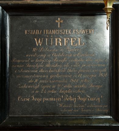 Zdjęcie nr 1: Płyta kamienna w formie kwadratu, ujęta drewnianą, profilowaną ramą. W polu złocona inskrypcja „KSIĄDZ FRANCISZEK KSAWERY / WÜRFEL / IIgi Proboszcz w Zawoi, / urodzony w Choliborzu w Czechach. / Pracował w tutejszej Parafii nietylko dla upięk/szenia Świątyni Pańskiej, ale i dla poświęcenia / i zbawienia dusz ludzkich Sobie powierzonych, / niezmordowaną gorliwością od 12 sierpn(ia) 1856 / do 10 października 1860 roku. / Zakończył życie w 49 roku wieku Swego, / a w 22 roku kapłaństwa. / Cześć Jego pamięci! Pokój Jego duszy! / W dowód miłości! / wdzięczni pa/rafianie wsi Zawoi i Skawicy.” Nad inskrypcją ryty krzyż łaciński.