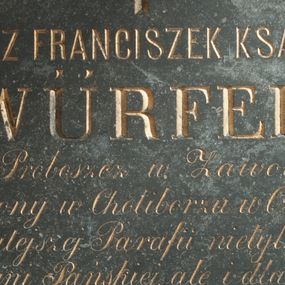 Zdjęcie nr 1: Płyta kamienna w formie kwadratu, ujęta drewnianą, profilowaną ramą. W polu złocona inskrypcja „KSIĄDZ FRANCISZEK KSAWERY / WÜRFEL / IIgi Proboszcz w Zawoi, / urodzony w Choliborzu w Czechach. / Pracował w tutejszej Parafii nietylko dla upięk/szenia Świątyni Pańskiej, ale i dla poświęcenia / i zbawienia dusz ludzkich Sobie powierzonych, / niezmordowaną gorliwością od 12 sierpn(ia) 1856 / do 10 października 1860 roku. / Zakończył życie w 49 roku wieku Swego, / a w 22 roku kapłaństwa. / Cześć Jego pamięci! Pokój Jego duszy! / W dowód miłości! / wdzięczni pa/rafianie wsi Zawoi i Skawicy.” Nad inskrypcją ryty krzyż łaciński.