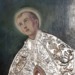 Zdjęcie nr 1: Obraz w formie stojącego prostokąta. W centrum św. Stanisław Kostka ukazany do pasa, zwrócony w trzech czwartych w prawo, z uniesioną głową oraz dłońmi złożonymi w geście modlitwy. Twarz ma pociągłą, o młodzieńczych rysach, oczach skierowanych w górę, małym nosie i pełnych ustach, okoloną krótkimi, jasnymi włosami. Wokół głowy ma nimb. W partii tułowia zakryty jest metalową, srebrzoną sukienką w postaci tuniki o kwiatowym wzorze, przepasanej w talii, na ramiona ma narzucony płaszcz o kwiatowym wzorze, z kołnierzykiem. Święty ukazany na cieniowanym, zielono-niebiesko-brązowym tle. W lewym dolnym rogu sygnatura „M. Sabatowicz / 1959”. 


