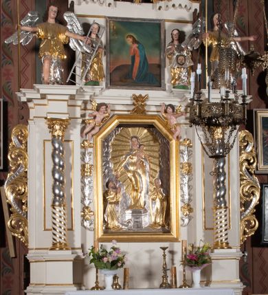 Zdjęcie nr 2: Nastawa architektoniczna, jednokondygnacyjna ze zwieńczeniem, ustawiona na dwustrefowym cokole, w górnej strefie z wyłamanymi, zdwojonymi prostopadłościanami. Ołtarz drewniany, prostopadłościenny, z drewnianą mensą. Antepedium ujęte profilowaną ramą, w polu na pomarańczowym tle namalowana korona otwarta z różańcem nad symetrycznie umieszczonymi liśćmi, z napisem „Królowo różańca świętego módl się za nami”. Nastawa ujęta parą kolumn o skręconych trzonach podzielonych na dwie strefy i kapitelach kompozytowych, ustawionych na tle wyłamanych ścianek bocznych nastawy. Podpory dźwigają pełne belkowanie, częściowo przerwane nad polem środkowym, wyłamane na ich osi. Na belkowaniu ustawione figury aniołów z arma Christi. Pole centralne wypełnione wnęką w formie stojącego prostokąta o ściętych górnych narożach, ujęte profilowaną ramą, z płaskorzeźbą Matki Boskiej Różańcowej. Wnęka flankowana ornamentem roślinnym, w przyłuczach dwa putta. Kondygnacja ujęta uszami utworzonymi z akantu i wstęgi. Zwieńczenie w formie leżącego prostokąta. W polu obraz Chrystusa w Ogrójcu o kształcie zbliżonym do kwadratu, ujęty profilowaną ramą. Obraz flankują figury św. Marii Magdaleny i św. Weroniki, nad którymi znajdują się baldachimy ze stylizowanym lambrekinem. Całość zwieńczona płaskorzeźbą tronującego Boga Ojca pośród obłoków i uskrzydlonych główek anielskich, w glorii promienistej. Struktura polichromowana w kolorze białym, profile złocone, kolumny, ornamentyka złocone i srebrzone. 


