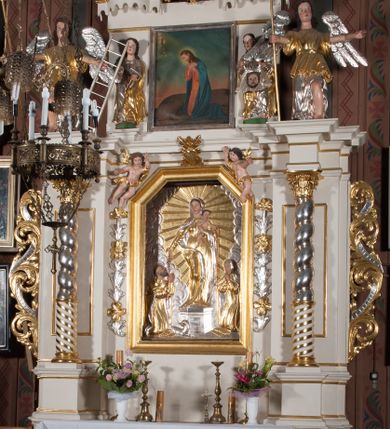 Zdjęcie nr 3: Nastawa architektoniczna, jednokondygnacyjna ze zwieńczeniem, ustawiona na dwustrefowym cokole, w górnej strefie z wyłamanymi, zdwojonymi prostopadłościanami. Ołtarz drewniany, prostopadłościenny, z drewnianą mensą. Antepedium ujęte profilowaną ramą, w polu na pomarańczowym tle namalowana korona otwarta z różańcem nad symetrycznie umieszczonymi liśćmi, z napisem „Królowo różańca świętego módl się za nami”. Nastawa ujęta parą kolumn o skręconych trzonach podzielonych na dwie strefy i kapitelach kompozytowych, ustawionych na tle wyłamanych ścianek bocznych nastawy. Podpory dźwigają pełne belkowanie, częściowo przerwane nad polem środkowym, wyłamane na ich osi. Na belkowaniu ustawione figury aniołów z arma Christi. Pole centralne wypełnione wnęką w formie stojącego prostokąta o ściętych górnych narożach, ujęte profilowaną ramą, z płaskorzeźbą Matki Boskiej Różańcowej. Wnęka flankowana ornamentem roślinnym, w przyłuczach dwa putta. Kondygnacja ujęta uszami utworzonymi z akantu i wstęgi. Zwieńczenie w formie leżącego prostokąta. W polu obraz Chrystusa w Ogrójcu o kształcie zbliżonym do kwadratu, ujęty profilowaną ramą. Obraz flankują figury św. Marii Magdaleny i św. Weroniki, nad którymi znajdują się baldachimy ze stylizowanym lambrekinem. Całość zwieńczona płaskorzeźbą tronującego Boga Ojca pośród obłoków i uskrzydlonych główek anielskich, w glorii promienistej. Struktura polichromowana w kolorze białym, profile złocone, kolumny, ornamentyka złocone i srebrzone. 


