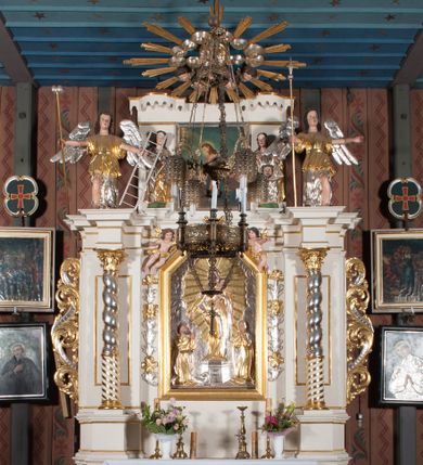 Zdjęcie nr 1: Nastawa architektoniczna, jednokondygnacyjna ze zwieńczeniem, ustawiona na dwustrefowym cokole, w górnej strefie z wyłamanymi, zdwojonymi prostopadłościanami. Ołtarz drewniany, prostopadłościenny, z drewnianą mensą. Antepedium ujęte profilowaną ramą, w polu na pomarańczowym tle namalowana korona otwarta z różańcem nad symetrycznie umieszczonymi liśćmi, z napisem „Królowo różańca świętego módl się za nami”. Nastawa ujęta parą kolumn o skręconych trzonach podzielonych na dwie strefy i kapitelach kompozytowych, ustawionych na tle wyłamanych ścianek bocznych nastawy. Podpory dźwigają pełne belkowanie, częściowo przerwane nad polem środkowym, wyłamane na ich osi. Na belkowaniu ustawione figury aniołów z arma Christi. Pole centralne wypełnione wnęką w formie stojącego prostokąta o ściętych górnych narożach, ujęte profilowaną ramą, z płaskorzeźbą Matki Boskiej Różańcowej. Wnęka flankowana ornamentem roślinnym, w przyłuczach dwa putta. Kondygnacja ujęta uszami utworzonymi z akantu i wstęgi. Zwieńczenie w formie leżącego prostokąta. W polu obraz Chrystusa w Ogrójcu o kształcie zbliżonym do kwadratu, ujęty profilowaną ramą. Obraz flankują figury św. Marii Magdaleny i św. Weroniki, nad którymi znajdują się baldachimy ze stylizowanym lambrekinem. Całość zwieńczona płaskorzeźbą tronującego Boga Ojca pośród obłoków i uskrzydlonych główek anielskich, w glorii promienistej. Struktura polichromowana w kolorze białym, profile złocone, kolumny, ornamentyka złocone i srebrzone. 


