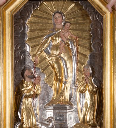 Zdjęcie nr 5: Nastawa architektoniczna, jednokondygnacyjna ze zwieńczeniem, ustawiona na dwustrefowym cokole, w górnej strefie z wyłamanymi, zdwojonymi prostopadłościanami. Ołtarz drewniany, prostopadłościenny, z drewnianą mensą. Antepedium ujęte profilowaną ramą, w polu na pomarańczowym tle namalowana korona otwarta z różańcem nad symetrycznie umieszczonymi liśćmi, z napisem „Królowo różańca świętego módl się za nami”. Nastawa ujęta parą kolumn o skręconych trzonach podzielonych na dwie strefy i kapitelach kompozytowych, ustawionych na tle wyłamanych ścianek bocznych nastawy. Podpory dźwigają pełne belkowanie, częściowo przerwane nad polem środkowym, wyłamane na ich osi. Na belkowaniu ustawione figury aniołów z arma Christi. Pole centralne wypełnione wnęką w formie stojącego prostokąta o ściętych górnych narożach, ujęte profilowaną ramą, z płaskorzeźbą Matki Boskiej Różańcowej. Wnęka flankowana ornamentem roślinnym, w przyłuczach dwa putta. Kondygnacja ujęta uszami utworzonymi z akantu i wstęgi. Zwieńczenie w formie leżącego prostokąta. W polu obraz Chrystusa w Ogrójcu o kształcie zbliżonym do kwadratu, ujęty profilowaną ramą. Obraz flankują figury św. Marii Magdaleny i św. Weroniki, nad którymi znajdują się baldachimy ze stylizowanym lambrekinem. Całość zwieńczona płaskorzeźbą tronującego Boga Ojca pośród obłoków i uskrzydlonych główek anielskich, w glorii promienistej. Struktura polichromowana w kolorze białym, profile złocone, kolumny, ornamentyka złocone i srebrzone. 


