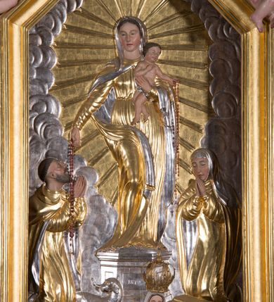 Zdjęcie nr 6: Nastawa architektoniczna, jednokondygnacyjna ze zwieńczeniem, ustawiona na dwustrefowym cokole, w górnej strefie z wyłamanymi, zdwojonymi prostopadłościanami. Ołtarz drewniany, prostopadłościenny, z drewnianą mensą. Antepedium ujęte profilowaną ramą, w polu na pomarańczowym tle namalowana korona otwarta z różańcem nad symetrycznie umieszczonymi liśćmi, z napisem „Królowo różańca świętego módl się za nami”. Nastawa ujęta parą kolumn o skręconych trzonach podzielonych na dwie strefy i kapitelach kompozytowych, ustawionych na tle wyłamanych ścianek bocznych nastawy. Podpory dźwigają pełne belkowanie, częściowo przerwane nad polem środkowym, wyłamane na ich osi. Na belkowaniu ustawione figury aniołów z arma Christi. Pole centralne wypełnione wnęką w formie stojącego prostokąta o ściętych górnych narożach, ujęte profilowaną ramą, z płaskorzeźbą Matki Boskiej Różańcowej. Wnęka flankowana ornamentem roślinnym, w przyłuczach dwa putta. Kondygnacja ujęta uszami utworzonymi z akantu i wstęgi. Zwieńczenie w formie leżącego prostokąta. W polu obraz Chrystusa w Ogrójcu o kształcie zbliżonym do kwadratu, ujęty profilowaną ramą. Obraz flankują figury św. Marii Magdaleny i św. Weroniki, nad którymi znajdują się baldachimy ze stylizowanym lambrekinem. Całość zwieńczona płaskorzeźbą tronującego Boga Ojca pośród obłoków i uskrzydlonych główek anielskich, w glorii promienistej. Struktura polichromowana w kolorze białym, profile złocone, kolumny, ornamentyka złocone i srebrzone. 


