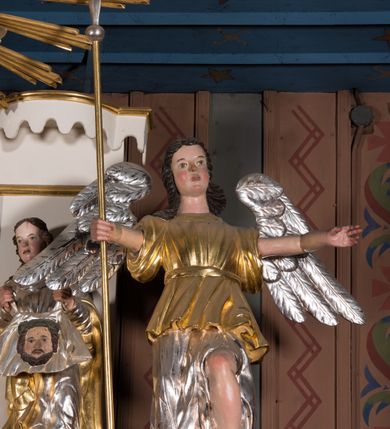 Zdjęcie nr 19: Nastawa architektoniczna, jednokondygnacyjna ze zwieńczeniem, ustawiona na dwustrefowym cokole, w górnej strefie z wyłamanymi, zdwojonymi prostopadłościanami. Ołtarz drewniany, prostopadłościenny, z drewnianą mensą. Antepedium ujęte profilowaną ramą, w polu na pomarańczowym tle namalowana korona otwarta z różańcem nad symetrycznie umieszczonymi liśćmi, z napisem „Królowo różańca świętego módl się za nami”. Nastawa ujęta parą kolumn o skręconych trzonach podzielonych na dwie strefy i kapitelach kompozytowych, ustawionych na tle wyłamanych ścianek bocznych nastawy. Podpory dźwigają pełne belkowanie, częściowo przerwane nad polem środkowym, wyłamane na ich osi. Na belkowaniu ustawione figury aniołów z arma Christi. Pole centralne wypełnione wnęką w formie stojącego prostokąta o ściętych górnych narożach, ujęte profilowaną ramą, z płaskorzeźbą Matki Boskiej Różańcowej. Wnęka flankowana ornamentem roślinnym, w przyłuczach dwa putta. Kondygnacja ujęta uszami utworzonymi z akantu i wstęgi. Zwieńczenie w formie leżącego prostokąta. W polu obraz Chrystusa w Ogrójcu o kształcie zbliżonym do kwadratu, ujęty profilowaną ramą. Obraz flankują figury św. Marii Magdaleny i św. Weroniki, nad którymi znajdują się baldachimy ze stylizowanym lambrekinem. Całość zwieńczona płaskorzeźbą tronującego Boga Ojca pośród obłoków i uskrzydlonych główek anielskich, w glorii promienistej. Struktura polichromowana w kolorze białym, profile złocone, kolumny, ornamentyka złocone i srebrzone. 


