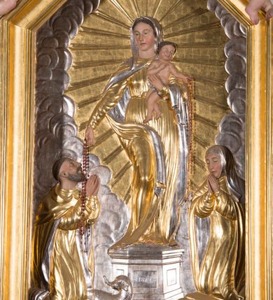 Zdjęcie nr 8: Nastawa architektoniczna, jednokondygnacyjna ze zwieńczeniem, ustawiona na dwustrefowym cokole, w górnej strefie z wyłamanymi, zdwojonymi prostopadłościanami. Ołtarz drewniany, prostopadłościenny, z drewnianą mensą. Antepedium ujęte profilowaną ramą, w polu na pomarańczowym tle namalowana korona otwarta z różańcem nad symetrycznie umieszczonymi liśćmi, z napisem „Królowo różańca świętego módl się za nami”. Nastawa ujęta parą kolumn o skręconych trzonach podzielonych na dwie strefy i kapitelach kompozytowych, ustawionych na tle wyłamanych ścianek bocznych nastawy. Podpory dźwigają pełne belkowanie, częściowo przerwane nad polem środkowym, wyłamane na ich osi. Na belkowaniu ustawione figury aniołów z arma Christi. Pole centralne wypełnione wnęką w formie stojącego prostokąta o ściętych górnych narożach, ujęte profilowaną ramą, z płaskorzeźbą Matki Boskiej Różańcowej. Wnęka flankowana ornamentem roślinnym, w przyłuczach dwa putta. Kondygnacja ujęta uszami utworzonymi z akantu i wstęgi. Zwieńczenie w formie leżącego prostokąta. W polu obraz Chrystusa w Ogrójcu o kształcie zbliżonym do kwadratu, ujęty profilowaną ramą. Obraz flankują figury św. Marii Magdaleny i św. Weroniki, nad którymi znajdują się baldachimy ze stylizowanym lambrekinem. Całość zwieńczona płaskorzeźbą tronującego Boga Ojca pośród obłoków i uskrzydlonych główek anielskich, w glorii promienistej. Struktura polichromowana w kolorze białym, profile złocone, kolumny, ornamentyka złocone i srebrzone. 


