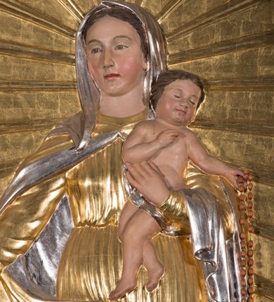 Zdjęcie nr 11: Nastawa architektoniczna, jednokondygnacyjna ze zwieńczeniem, ustawiona na dwustrefowym cokole, w górnej strefie z wyłamanymi, zdwojonymi prostopadłościanami. Ołtarz drewniany, prostopadłościenny, z drewnianą mensą. Antepedium ujęte profilowaną ramą, w polu na pomarańczowym tle namalowana korona otwarta z różańcem nad symetrycznie umieszczonymi liśćmi, z napisem „Królowo różańca świętego módl się za nami”. Nastawa ujęta parą kolumn o skręconych trzonach podzielonych na dwie strefy i kapitelach kompozytowych, ustawionych na tle wyłamanych ścianek bocznych nastawy. Podpory dźwigają pełne belkowanie, częściowo przerwane nad polem środkowym, wyłamane na ich osi. Na belkowaniu ustawione figury aniołów z arma Christi. Pole centralne wypełnione wnęką w formie stojącego prostokąta o ściętych górnych narożach, ujęte profilowaną ramą, z płaskorzeźbą Matki Boskiej Różańcowej. Wnęka flankowana ornamentem roślinnym, w przyłuczach dwa putta. Kondygnacja ujęta uszami utworzonymi z akantu i wstęgi. Zwieńczenie w formie leżącego prostokąta. W polu obraz Chrystusa w Ogrójcu o kształcie zbliżonym do kwadratu, ujęty profilowaną ramą. Obraz flankują figury św. Marii Magdaleny i św. Weroniki, nad którymi znajdują się baldachimy ze stylizowanym lambrekinem. Całość zwieńczona płaskorzeźbą tronującego Boga Ojca pośród obłoków i uskrzydlonych główek anielskich, w glorii promienistej. Struktura polichromowana w kolorze białym, profile złocone, kolumny, ornamentyka złocone i srebrzone. 


