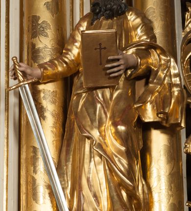 Zdjęcie nr 25: Nastawa architektoniczna, jednokondygnacyjna ze zwieńczeniem, jednoosiowa z bramkami, ustawiona na dwustrefowym cokole, z wyłamanymi pod kątem dwiema parami prostopadłościanów w górnej strefie. Ołtarz kamienny, prostopadłościenny, w drewnianej obudowie, z drewnianą mensą. Antepedium ujęte profilowaną ramą, w centrum medalion z krzyżem o trójlistnym zakończeniu ramion i promieniami na ich skrzyżowaniu, po bokach monogramy maryjny i IHS. Na ołtarzu tabernakulum z tronem wystawienia. Nastawa ujęta dwiema parami kolumn, przedzielonych dwiema parami filarów o kanelowanych trzonach, ustawionych pod kątem. Podpory dźwigają pełne belkowanie, wyłamane pod kątem na ich osi, przerwane nad polem środkowym oraz fragmenty przerwanego, półkolistego przyczółka z siedzącymi na nich puttami. Pomiędzy kolumnami ustawione figury św. Piotra i św. Pawła. W polu środkowym wnęka z obrazem św. Klemensa w formie stojącego prostokąta zakończona łukiem segmentowym z uskokiem, ujęta profilowaną ramą zwieńczoną dwiema zwróconymi ku sobie wolutami, podtrzymującymi koronę otwartą, flankowaną przez dwa putta. Kondygnacja ujęta uszami utworzonymi z suchego akantu i wstęgi. Zwieńczenie o kształcie zbliżonym do leżącego prostokąta, zamkniętego fragmentem segmentowo wyłamanego gzymsu, flankowanego spływami wolutowymi. Całe pole wypełnia obraz Zwiastowania, ujęty liśćmi. Zwieńczenie zakończone płaskorzeźbionym przedstawieniem Trójcy Świętej pośród obłoków i uskrzydlonych główek anielskich, w glorii promienistej. Bramki flankowane pilastrami o kanelowanych trzonach, podtrzymującymi nadproże wyłamane na kształt łuku kotarowego, zwieńczone kluczami z puttami. Na osi pilastrów ustawione po dwa wazony. Przejścia w formie stojącego prostokąta zamkniętego łukiem segmentowym nadwieszonym. Struktura polichromowana w kolorze białym; kolumny, profile i ornamentyka złocone, detal srebrzony. Z tyłu ołtarza ryta inskrypcja: „I.L.O.Z / 9/5 1845”.