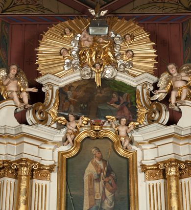 Zdjęcie nr 12: Nastawa architektoniczna, jednokondygnacyjna ze zwieńczeniem, jednoosiowa z bramkami, ustawiona na dwustrefowym cokole, z wyłamanymi pod kątem dwiema parami prostopadłościanów w górnej strefie. Ołtarz kamienny, prostopadłościenny, w drewnianej obudowie, z drewnianą mensą. Antepedium ujęte profilowaną ramą, w centrum medalion z krzyżem o trójlistnym zakończeniu ramion i promieniami na ich skrzyżowaniu, po bokach monogramy maryjny i IHS. Na ołtarzu tabernakulum z tronem wystawienia. Nastawa ujęta dwiema parami kolumn, przedzielonych dwiema parami filarów o kanelowanych trzonach, ustawionych pod kątem. Podpory dźwigają pełne belkowanie, wyłamane pod kątem na ich osi, przerwane nad polem środkowym oraz fragmenty przerwanego, półkolistego przyczółka z siedzącymi na nich puttami. Pomiędzy kolumnami ustawione figury św. Piotra i św. Pawła. W polu środkowym wnęka z obrazem św. Klemensa w formie stojącego prostokąta zakończona łukiem segmentowym z uskokiem, ujęta profilowaną ramą zwieńczoną dwiema zwróconymi ku sobie wolutami, podtrzymującymi koronę otwartą, flankowaną przez dwa putta. Kondygnacja ujęta uszami utworzonymi z suchego akantu i wstęgi. Zwieńczenie o kształcie zbliżonym do leżącego prostokąta, zamkniętego fragmentem segmentowo wyłamanego gzymsu, flankowanego spływami wolutowymi. Całe pole wypełnia obraz Zwiastowania, ujęty liśćmi. Zwieńczenie zakończone płaskorzeźbionym przedstawieniem Trójcy Świętej pośród obłoków i uskrzydlonych główek anielskich, w glorii promienistej. Bramki flankowane pilastrami o kanelowanych trzonach, podtrzymującymi nadproże wyłamane na kształt łuku kotarowego, zwieńczone kluczami z puttami. Na osi pilastrów ustawione po dwa wazony. Przejścia w formie stojącego prostokąta zamkniętego łukiem segmentowym nadwieszonym. Struktura polichromowana w kolorze białym; kolumny, profile i ornamentyka złocone, detal srebrzony. Z tyłu ołtarza ryta inskrypcja: „I.L.O.Z / 9/5 1845”.