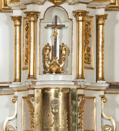 Zdjęcie nr 14: Nastawa architektoniczna, jednokondygnacyjna ze zwieńczeniem, jednoosiowa z bramkami, ustawiona na dwustrefowym cokole, z wyłamanymi pod kątem dwiema parami prostopadłościanów w górnej strefie. Ołtarz kamienny, prostopadłościenny, w drewnianej obudowie, z drewnianą mensą. Antepedium ujęte profilowaną ramą, w centrum medalion z krzyżem o trójlistnym zakończeniu ramion i promieniami na ich skrzyżowaniu, po bokach monogramy maryjny i IHS. Na ołtarzu tabernakulum z tronem wystawienia. Nastawa ujęta dwiema parami kolumn, przedzielonych dwiema parami filarów o kanelowanych trzonach, ustawionych pod kątem. Podpory dźwigają pełne belkowanie, wyłamane pod kątem na ich osi, przerwane nad polem środkowym oraz fragmenty przerwanego, półkolistego przyczółka z siedzącymi na nich puttami. Pomiędzy kolumnami ustawione figury św. Piotra i św. Pawła. W polu środkowym wnęka z obrazem św. Klemensa w formie stojącego prostokąta zakończona łukiem segmentowym z uskokiem, ujęta profilowaną ramą zwieńczoną dwiema zwróconymi ku sobie wolutami, podtrzymującymi koronę otwartą, flankowaną przez dwa putta. Kondygnacja ujęta uszami utworzonymi z suchego akantu i wstęgi. Zwieńczenie o kształcie zbliżonym do leżącego prostokąta, zamkniętego fragmentem segmentowo wyłamanego gzymsu, flankowanego spływami wolutowymi. Całe pole wypełnia obraz Zwiastowania, ujęty liśćmi. Zwieńczenie zakończone płaskorzeźbionym przedstawieniem Trójcy Świętej pośród obłoków i uskrzydlonych główek anielskich, w glorii promienistej. Bramki flankowane pilastrami o kanelowanych trzonach, podtrzymującymi nadproże wyłamane na kształt łuku kotarowego, zwieńczone kluczami z puttami. Na osi pilastrów ustawione po dwa wazony. Przejścia w formie stojącego prostokąta zamkniętego łukiem segmentowym nadwieszonym. Struktura polichromowana w kolorze białym; kolumny, profile i ornamentyka złocone, detal srebrzony. Z tyłu ołtarza ryta inskrypcja: „I.L.O.Z / 9/5 1845”.