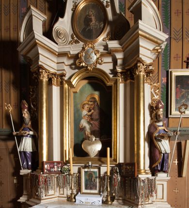 Zdjęcie nr 1: Nastawa architektoniczna, jednoosiowa, jednokondygnacyjna ze zwieńczeniem, ustawiona na dwustrefowym cokole, w górnej części z wyłamanymi pod kątem dwoma prostopadłościanami. Ołtarz drewniany, prostopadłościenny, skrzyniowy, z drewnianą mensą. Antepedium ujęte profilowaną ramą, w polu dwie duże, płaskorzeźbione rozety na pomarańczowym tle. Nastawa ujęta parą kolumn ustawionych na tle pilastrów, dźwigających pełne belkowanie, wyłamane pod kątem na ich osi, częściowo przerwane nad polem środkowym oraz fragmenty przerwanego półkolistego przyczółka. Pole centralne w całości wypełnione wnęką w formie stojącego prostokąta zamkniętego łukiem segmentowym nadwieszonym, ujętym profilowaną ramą, z obrazem św. Antoniego Padewskiego. Nad nim akantowy kartusz, z przedstawieniem dwóch skrzyżowanych kluczy w polu. Kondygnację flankują dwie figury biskupów ustawione na wysuniętych krawędziach cokołu oraz uszy utworzone z suchego akantu i wstęgi. Zwieńczenie w formie zbliżonej do trapezu zamkniętego fragmentem gzymsu o kształcie łuku segmentowego z uskokiem, flankowanego spływami wolutowymi. W polu obraz św. Antoniego Padewskiego w formie stojącego owalu, ujęty profilowaną ramą, u góry dekorowany zwisami kwiatowymi, u dołu liśćmi. Całość zakończona figurką św. Michała Archanioła trzymającego w uniesionej ręce miecz. Struktura polichromowana w kolorze białym; kolumny, profile i ornamentyka złocone, detal srebrzony. 


