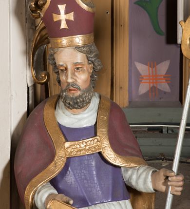 Zdjęcie nr 9: Nastawa architektoniczna, jednoosiowa, jednokondygnacyjna ze zwieńczeniem, ustawiona na dwustrefowym cokole, w górnej części z wyłamanymi pod kątem dwoma prostopadłościanami. Ołtarz drewniany, prostopadłościenny, skrzyniowy, z drewnianą mensą. Antepedium ujęte profilowaną ramą, w polu dwie duże, płaskorzeźbione rozety na pomarańczowym tle. Nastawa ujęta parą kolumn ustawionych na tle pilastrów, dźwigających pełne belkowanie, wyłamane pod kątem na ich osi, częściowo przerwane nad polem środkowym oraz fragmenty przerwanego półkolistego przyczółka. Pole centralne w całości wypełnione wnęką w formie stojącego prostokąta zamkniętego łukiem segmentowym nadwieszonym, ujętym profilowaną ramą, z obrazem św. Antoniego Padewskiego. Nad nim akantowy kartusz, z przedstawieniem dwóch skrzyżowanych kluczy w polu. Kondygnację flankują dwie figury biskupów ustawione na wysuniętych krawędziach cokołu oraz uszy utworzone z suchego akantu i wstęgi. Zwieńczenie w formie zbliżonej do trapezu zamkniętego fragmentem gzymsu o kształcie łuku segmentowego z uskokiem, flankowanego spływami wolutowymi. W polu obraz św. Antoniego Padewskiego w formie stojącego owalu, ujęty profilowaną ramą, u góry dekorowany zwisami kwiatowymi, u dołu liśćmi. Całość zakończona figurką św. Michała Archanioła trzymającego w uniesionej ręce miecz. Struktura polichromowana w kolorze białym; kolumny, profile i ornamentyka złocone, detal srebrzony. 


