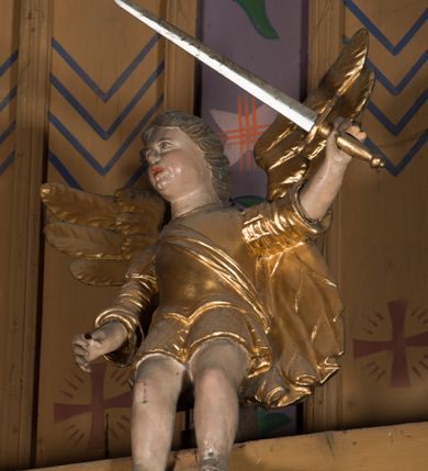 Zdjęcie nr 16: Nastawa architektoniczna, jednoosiowa, jednokondygnacyjna ze zwieńczeniem, ustawiona na dwustrefowym cokole, w górnej części z wyłamanymi pod kątem dwoma prostopadłościanami. Ołtarz drewniany, prostopadłościenny, skrzyniowy, z drewnianą mensą. Antepedium ujęte profilowaną ramą, w polu dwie duże, płaskorzeźbione rozety na pomarańczowym tle. Nastawa ujęta parą kolumn ustawionych na tle pilastrów, dźwigających pełne belkowanie, wyłamane pod kątem na ich osi, częściowo przerwane nad polem środkowym oraz fragmenty przerwanego półkolistego przyczółka. Pole centralne w całości wypełnione wnęką w formie stojącego prostokąta zamkniętego łukiem segmentowym nadwieszonym, ujętym profilowaną ramą, z obrazem św. Antoniego Padewskiego. Nad nim akantowy kartusz, z przedstawieniem dwóch skrzyżowanych kluczy w polu. Kondygnację flankują dwie figury biskupów ustawione na wysuniętych krawędziach cokołu oraz uszy utworzone z suchego akantu i wstęgi. Zwieńczenie w formie zbliżonej do trapezu zamkniętego fragmentem gzymsu o kształcie łuku segmentowego z uskokiem, flankowanego spływami wolutowymi. W polu obraz św. Antoniego Padewskiego w formie stojącego owalu, ujęty profilowaną ramą, u góry dekorowany zwisami kwiatowymi, u dołu liśćmi. Całość zakończona figurką św. Michała Archanioła trzymającego w uniesionej ręce miecz. Struktura polichromowana w kolorze białym; kolumny, profile i ornamentyka złocone, detal srebrzony. 


