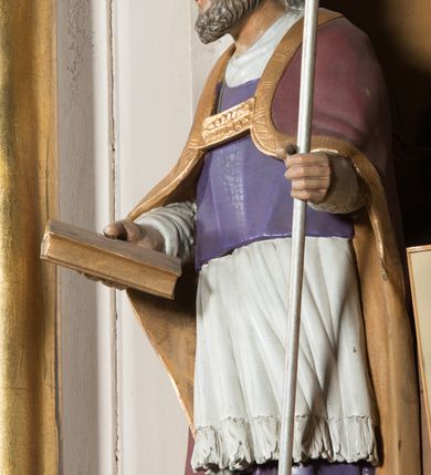 Zdjęcie nr 11: Nastawa architektoniczna, jednoosiowa, jednokondygnacyjna ze zwieńczeniem, ustawiona na dwustrefowym cokole, w górnej części z wyłamanymi pod kątem dwoma prostopadłościanami. Ołtarz drewniany, prostopadłościenny, skrzyniowy, z drewnianą mensą. Antepedium ujęte profilowaną ramą, w polu dwie duże, płaskorzeźbione rozety na pomarańczowym tle. Nastawa ujęta parą kolumn ustawionych na tle pilastrów, dźwigających pełne belkowanie, wyłamane pod kątem na ich osi, częściowo przerwane nad polem środkowym oraz fragmenty przerwanego półkolistego przyczółka. Pole centralne w całości wypełnione wnęką w formie stojącego prostokąta zamkniętego łukiem segmentowym nadwieszonym, ujętym profilowaną ramą, z obrazem św. Antoniego Padewskiego. Nad nim akantowy kartusz, z przedstawieniem dwóch skrzyżowanych kluczy w polu. Kondygnację flankują dwie figury biskupów ustawione na wysuniętych krawędziach cokołu oraz uszy utworzone z suchego akantu i wstęgi. Zwieńczenie w formie zbliżonej do trapezu zamkniętego fragmentem gzymsu o kształcie łuku segmentowego z uskokiem, flankowanego spływami wolutowymi. W polu obraz św. Antoniego Padewskiego w formie stojącego owalu, ujęty profilowaną ramą, u góry dekorowany zwisami kwiatowymi, u dołu liśćmi. Całość zakończona figurką św. Michała Archanioła trzymającego w uniesionej ręce miecz. Struktura polichromowana w kolorze białym; kolumny, profile i ornamentyka złocone, detal srebrzony. 


