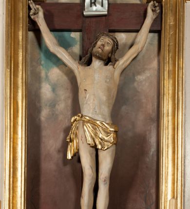 Zdjęcie nr 3: Nastawa architektoniczna, jednoosiowa, jednokondygnacyjna ze zwieńczeniem, ustawiona na dwustrefowym cokole, w górnej części z wyłamanymi pod kątem dwoma prostopadłościanami. Ołtarz drewniany, prostopadłościenny, skrzyniowy, z drewnianą mensą. Antepedium ujęte profilowaną ramą, w polu dwie, duże, płaskorzeźbione rozety na pomarańczowym tle. Nastawa ujęta parą kolumn ustawionych na tle pilastrów, dźwigających pełne belkowanie, wyłamane pod kątem na ich osi, częściowo przerwane nad polem środkowym, oraz fragmenty przerwanego półkolistego przyczółka z puttami. Pole centralne w całości wypełnione wnęką w formie stojącego prostokąta zamkniętego łukiem segmentowym nadwieszonym, ujętym profilowaną ramą, z wpisanym krucyfiksem na tle malowanych obłoków. Nad nim akantowo-wstęgowy kartusz, z napisem „OJCZE! / odpuść im / bo niewiedzą / co czynią”. Kondygnację flankują figury Matki Boskiej i św. Jana ustawione na wysuniętych krawędziach cokołu oraz uszy utworzone z suchego akantu i wstęgi. Zwieńczenie w formie zbliżonej do trapezu zamkniętego fragmentem gzymsu o kształcie łuku segmentowego z uskokiem, flankowanego spływami wolutowymi. W polu obraz Piety w formie stojącego owalu, ujęty profilowaną ramą, u góry dekorowany zwisami kwiatowymi, u dołu liśćmi. Całość zakończona figurą Anioła Stróża. Struktura polichromowana w kolorze białym; kolumny, profile i ornamentyka złocone, detal srebrzony. 