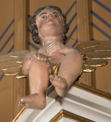 Zdjęcie nr 11: Nastawa architektoniczna, jednoosiowa, jednokondygnacyjna ze zwieńczeniem, ustawiona na dwustrefowym cokole, w górnej części z wyłamanymi pod kątem dwoma prostopadłościanami. Ołtarz drewniany, prostopadłościenny, skrzyniowy, z drewnianą mensą. Antepedium ujęte profilowaną ramą, w polu dwie, duże, płaskorzeźbione rozety na pomarańczowym tle. Nastawa ujęta parą kolumn ustawionych na tle pilastrów, dźwigających pełne belkowanie, wyłamane pod kątem na ich osi, częściowo przerwane nad polem środkowym, oraz fragmenty przerwanego półkolistego przyczółka z puttami. Pole centralne w całości wypełnione wnęką w formie stojącego prostokąta zamkniętego łukiem segmentowym nadwieszonym, ujętym profilowaną ramą, z wpisanym krucyfiksem na tle malowanych obłoków. Nad nim akantowo-wstęgowy kartusz, z napisem „OJCZE! / odpuść im / bo niewiedzą / co czynią”. Kondygnację flankują figury Matki Boskiej i św. Jana ustawione na wysuniętych krawędziach cokołu oraz uszy utworzone z suchego akantu i wstęgi. Zwieńczenie w formie zbliżonej do trapezu zamkniętego fragmentem gzymsu o kształcie łuku segmentowego z uskokiem, flankowanego spływami wolutowymi. W polu obraz Piety w formie stojącego owalu, ujęty profilowaną ramą, u góry dekorowany zwisami kwiatowymi, u dołu liśćmi. Całość zakończona figurą Anioła Stróża. Struktura polichromowana w kolorze białym; kolumny, profile i ornamentyka złocone, detal srebrzony. 